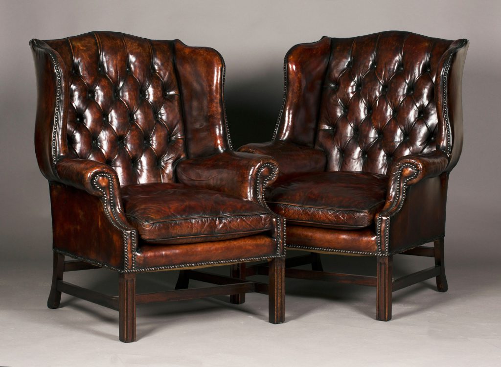 A pair of 20th Century George III style buttoned brown leather wing back armchairs sold for a hammer price of £1400