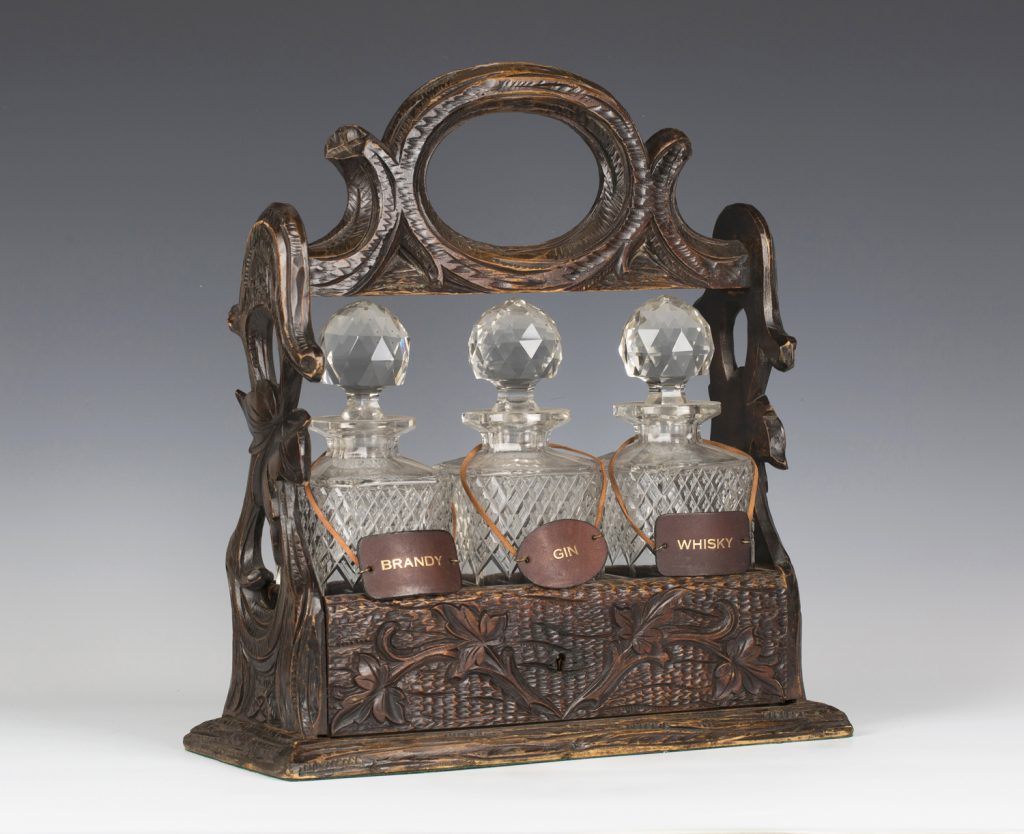 A late 19th century Black Forest carved softwood three bottle tantalus from the Lenson-Smith Collection
